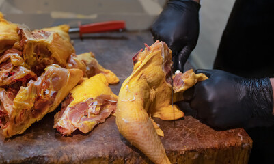 Butcher prep cuts chicken on wooden cutting board. Fresh and healthy food preparation concept