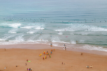 Aerial view of the beach in Biarritz, France. Surfers on the beach and in the ocean. Active holidays in France. - obrazy, fototapety, plakaty