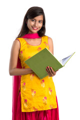 Pretty young girl holding book and posing on white background