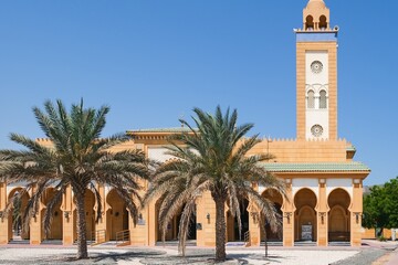 Fototapeta na wymiar View to urban Mosque in typical moroccan style wit h majestic minaret and archways gallery, covered white arabesque mosaic tiles located in Abu Dhabi,UAE