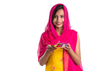 Beautiful Indian young girl holding pooja thali or performing worship on a white background