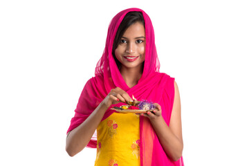 Beautiful Indian young girl holding pooja thali or performing worship on a white background