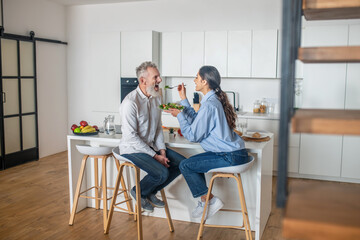 Dark-haired young woman feeding her husband and smiling