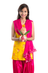 Indian girl holding a traditional copper Kalash, Indian Festival, copper Kalash with coconut and mango leaf with floral decoration, essential in Hindu Pooja.