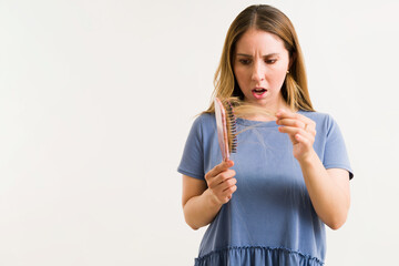 Shocked woman looking at hair in her brush