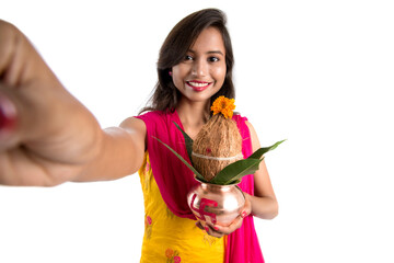 Beautiful young happy girl taking selfie with Kalash using a camera or smartphone on a white...