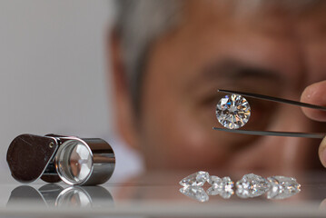 Close up of diamond dealer's hands evaluating diamond at international jewelry exhibition. High quality photo - obrazy, fototapety, plakaty