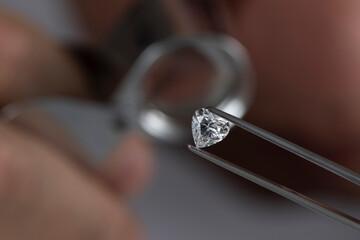 Close up of diamond dealer's hands evaluating diamond at international jewelry exhibition. High quality photo