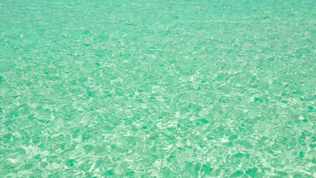 Sea surface in a turquoise lagoon, top view. The texture of sea water. Transparent turquoise sea water, natural background. Summer and travel vacation concept.