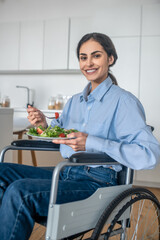 Positive handicapped young woman at home having lunch