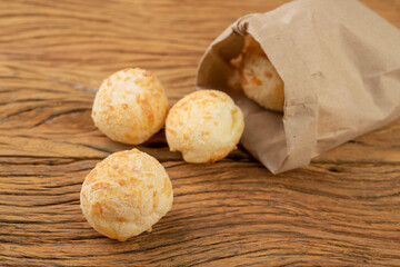 Typical brazilian cheese bun in a paper bag over a wooden board