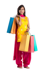 Beautiful Indian young girl holding and posing with shopping bags on a white background