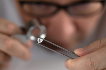 Close up of diamond dealer's hands evaluating diamond at international jewelry exhibition. High quality photo