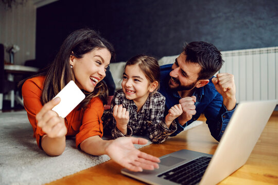 Happy Family Using Laptop For Online Shopping. They Are Excited For Purchase. Mom Holding Credit Card.