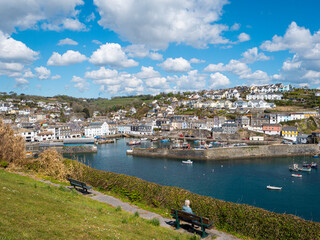 Naklejka na ściany i meble Overlooking a busy harbour with moored leisure and working boats at the picturesque fishing village and port of Mevagissey on the south coast of Cornwall, UK. Blue sky with cotton-wool clouds.