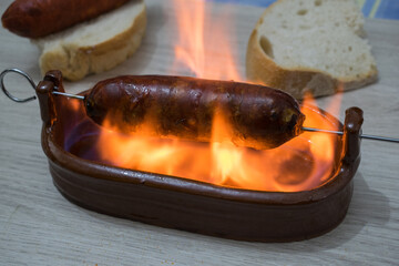 Chorizo ​​al infierno, typical dish of Spanish cuisine. Chorizo ​​in a clay bowl with alcohol