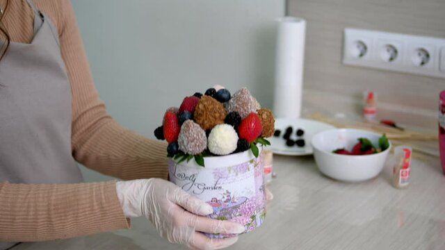 Girl in white gloves shows off gift of strawberries in chocolate