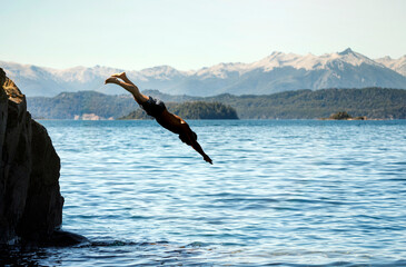 man alone jumping into the water from a cliff. Lago Nahuel Huapi, Patagonia, Argentina. Freedom adventure happiness concept