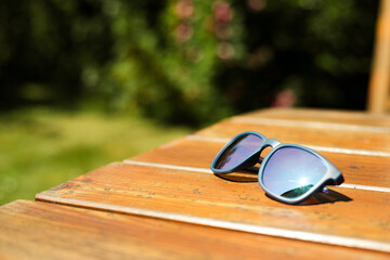 Fototapeta na wymiar Holiday and vacation - blue sunglasses on the wooden table in the garden