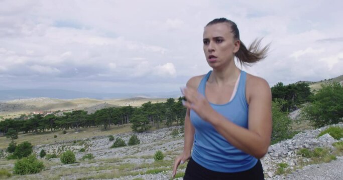 Determined sporty woman running trail alone on the road and preparing for a marathon. Sport and freedom concept.