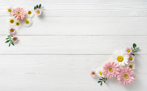 Flowers composition. White flowers on white wooden background. Wedding mockup with pink and white flowers. Flat lay, top view, frame. Gerbera, chamomile flowers.