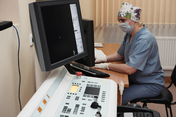 Fototapeta na wymiar A woman radiologist behind the monitor makes an X-ray correction.