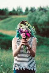 girl covering her face behind a bouquet of freshly picked flowers