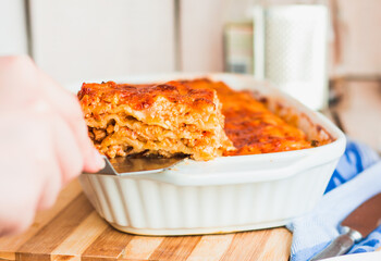 Young woman hands holding freshly fed meat lasagna on a white plate. Italian cuisine.Kinfolk and comfort food atmosphere concept