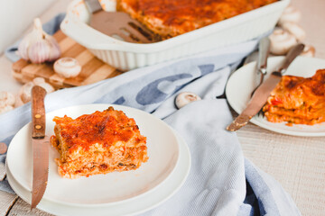 Slice of delicious beef lasagne with cheese crust on a white plate viewed close up on the side showing the layers.Restaurant menu, recipe