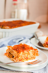 Slice of delicious beef lasagne with cheese crust on a white plate viewed close up on the side showing the layers.Restaurant menu, recipe