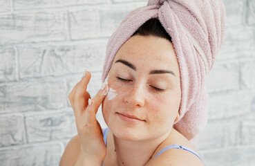 woman applying cream on face
