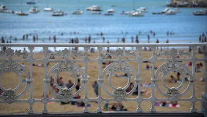 la barandilla de la playa de la concha en San sebastian con gente en la playa detrás. 