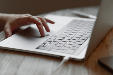 The girl works at home for a laptop. Hand on the touchpad, finger clicks on information.