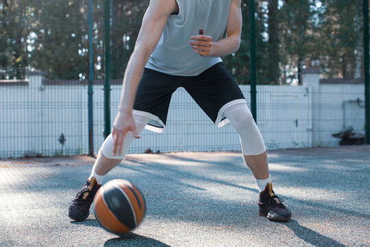 Professional male american basketball player in action with ball training on court outdoors, close up cropped photo