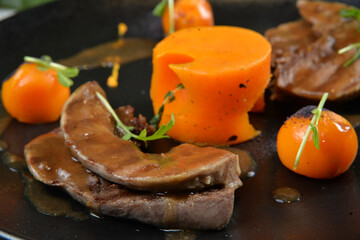 lamb tongue with spicy pumpkin on dark plate closeup