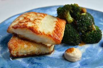 fish steak with grilled brokkoli on blue plate