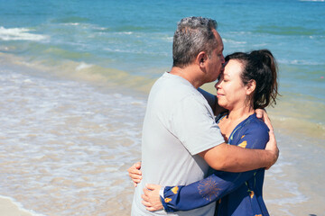 Fototapeta na wymiar Mature couple cuddling standing on the beach