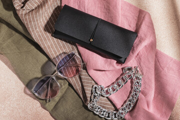 Gradient sunglasses, black eyeglass case and a large metal chain on multicolored fabric