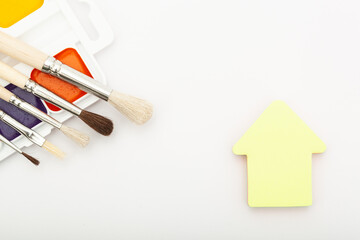 Paint palette with tassels and house stickers on a white background