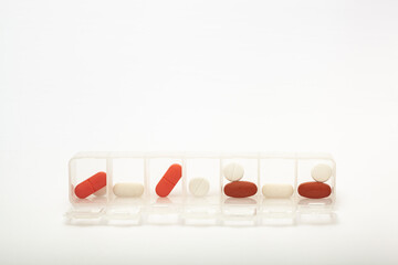 Capsules lie in a pill box on a white background. Box for packing tablets for a week