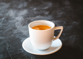 White cup of latte coffee on a black slate table.