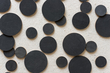 close up of black discs or circles on millboard - photographed from above in a top down style 