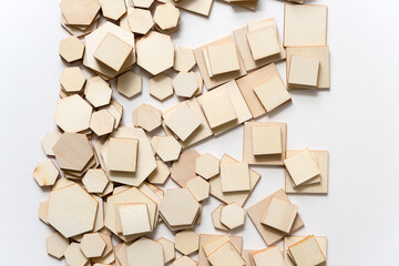 various hexagonal and square wooden shapes piled and layered randomly on white
