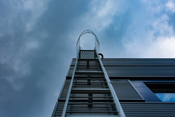 Stairway to Heaven. Metal staircase on the building against the background of the sky and clouds.