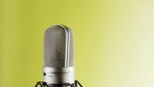 Studio microphone on an anti vibration stand, rotating. Professional audio recording equipment on yellow to white background