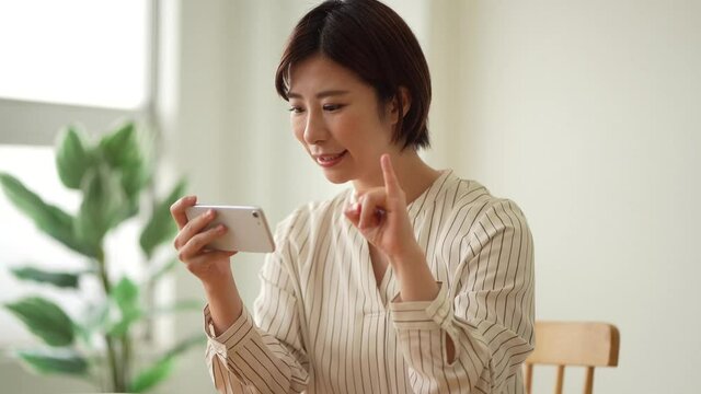 スマートフォンで手話の指文字を勉強する女性