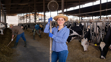 Female farmer posing in cowshed at dairy farm