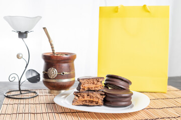 Alfajores Argentinos de chocolate y dulce de leche acompañado de mate y café, en fondo rojo, amarillo y negro