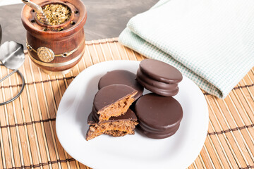 Alfajores Argentinos de chocolate y dulce de leche acompañado de mate y café, en fondo rojo,...