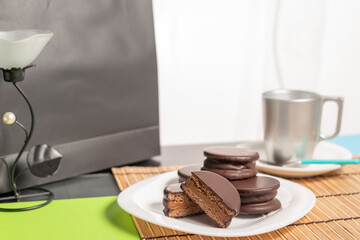 Alfajores Argentinos de chocolate y dulce de leche acompañado de mate y café, en fondo rojo, amarillo y negro